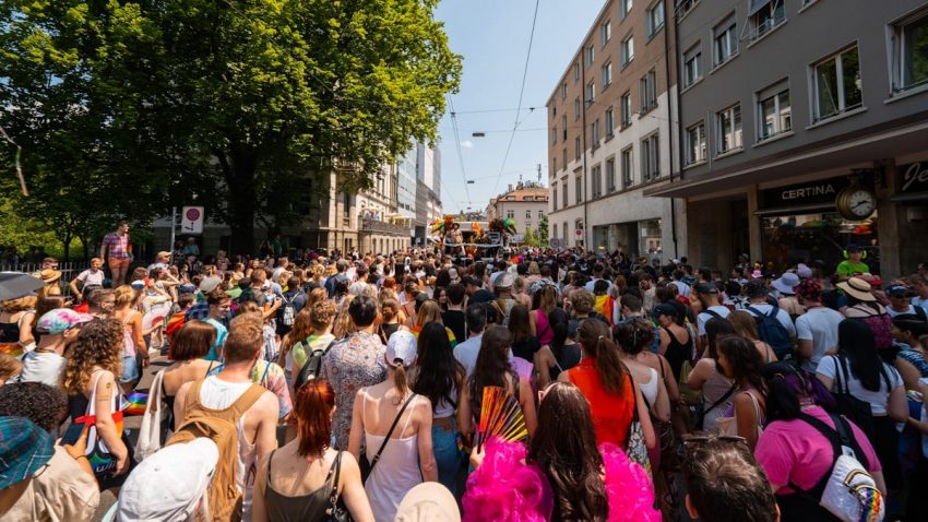 a crowd of people walking down a street next to tall buildings